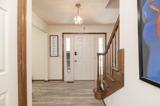 foyer with stairway, visible vents, baseboards, and light wood finished floors