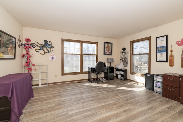 home office with plenty of natural light, baseboards, and light wood-style floors