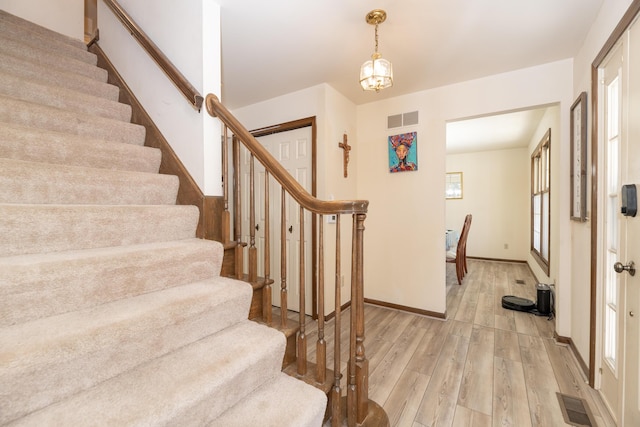 entrance foyer featuring light wood finished floors, visible vents, stairs, and baseboards