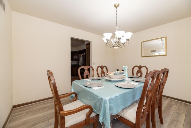 dining area with visible vents, a notable chandelier, light wood-style floors, and baseboards