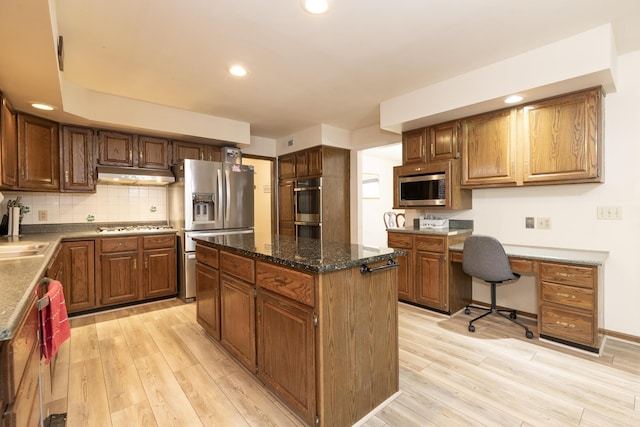 kitchen with under cabinet range hood, appliances with stainless steel finishes, light wood-style flooring, and a sink