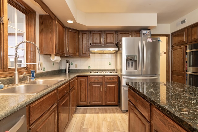 kitchen with visible vents, light wood-type flooring, a sink, under cabinet range hood, and appliances with stainless steel finishes