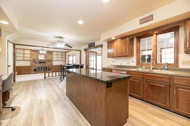 kitchen with a sink, light wood-type flooring, a fireplace, and a center island