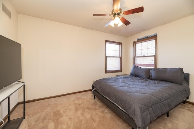 bedroom with visible vents, light colored carpet, baseboards, and ceiling fan