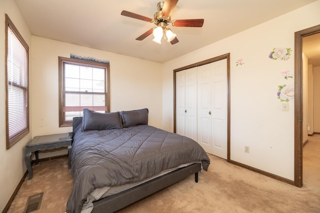 bedroom featuring visible vents, baseboards, ceiling fan, a closet, and light carpet