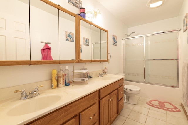 bathroom featuring a sink, bath / shower combo with glass door, double vanity, and tile patterned floors