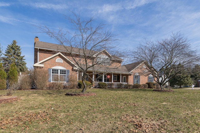 view of front of home featuring brick siding, a chimney, and a front lawn