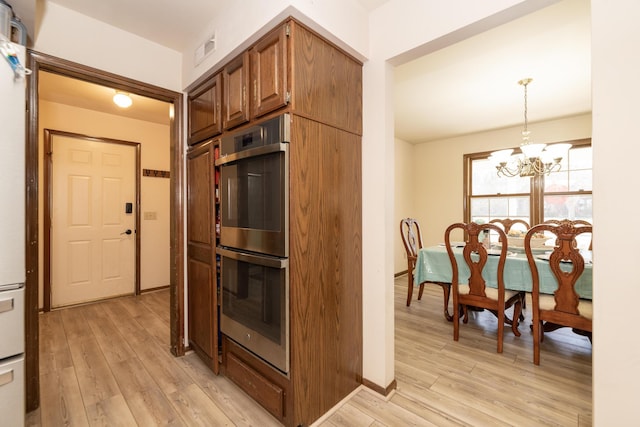 kitchen featuring double oven, a notable chandelier, visible vents, and light wood finished floors