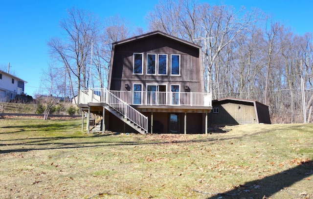 back of property with a deck, an outbuilding, stairway, and a lawn