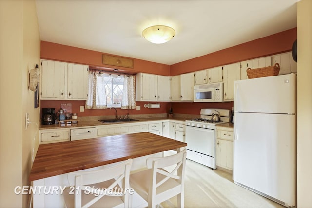 kitchen with white appliances, butcher block counters, and a sink