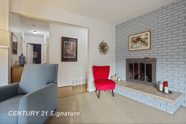 living area with visible vents, a fireplace, baseboards, and wood finished floors