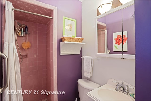 bathroom featuring toilet, tiled shower, and a sink