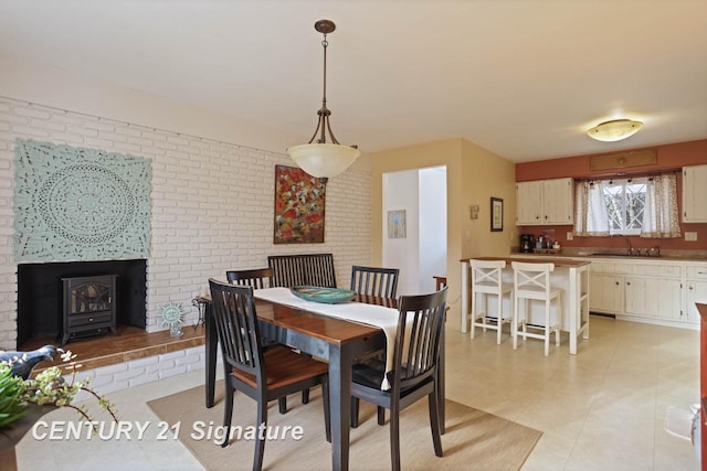 dining space with light tile patterned floors, brick wall, and a wood stove