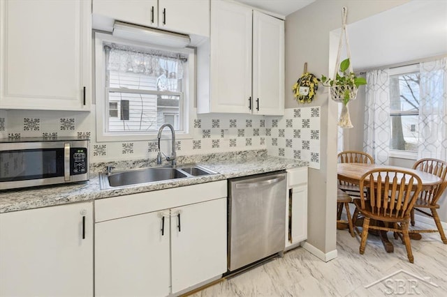 kitchen featuring decorative backsplash, appliances with stainless steel finishes, white cabinetry, and a sink