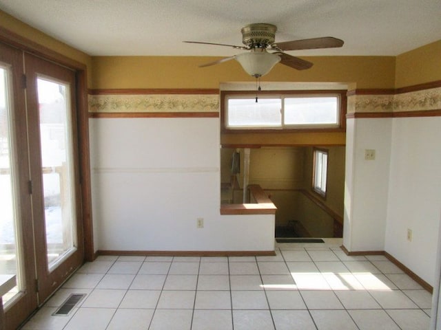 unfurnished room with light tile patterned floors, visible vents, a healthy amount of sunlight, and a ceiling fan