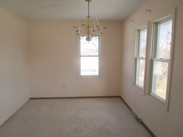 unfurnished room with baseboards, light carpet, plenty of natural light, and a chandelier