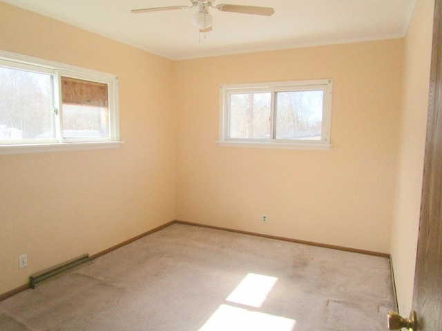 empty room featuring a wealth of natural light, visible vents, light colored carpet, and ceiling fan