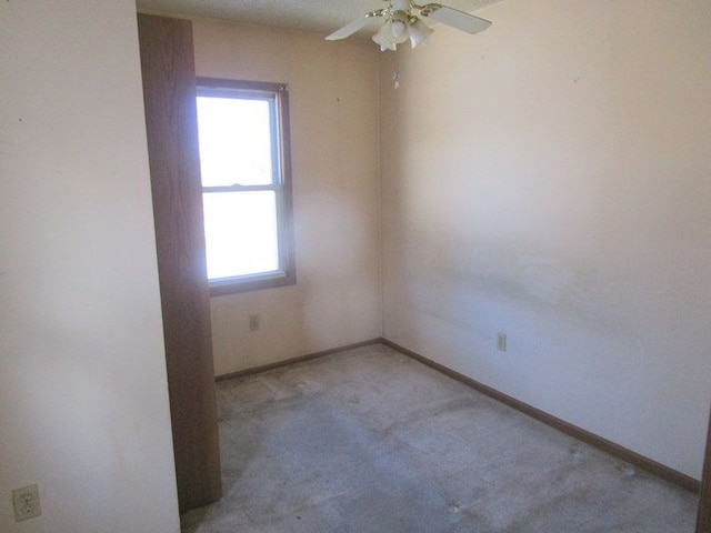 spare room featuring light carpet, baseboards, and ceiling fan