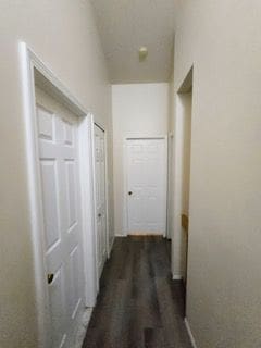 corridor featuring lofted ceiling and dark wood-style flooring