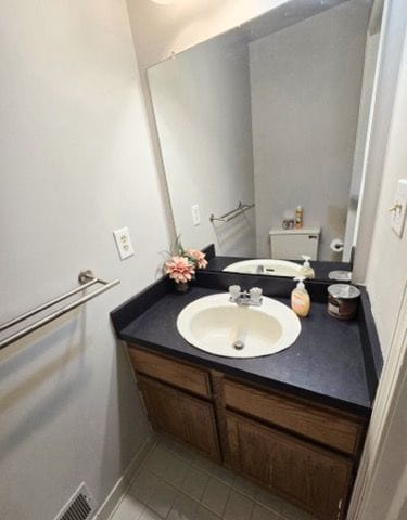 half bath with tile patterned flooring, toilet, and vanity