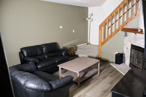 living room featuring a fireplace, stairway, and wood finished floors