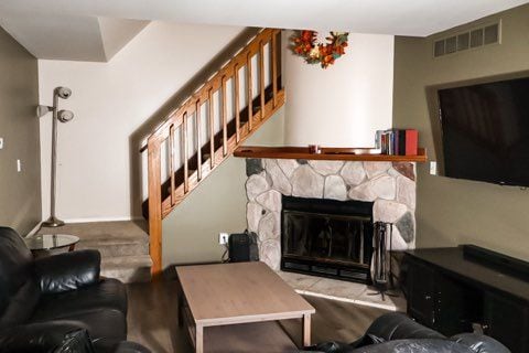 living room featuring visible vents, a stone fireplace, and stairway