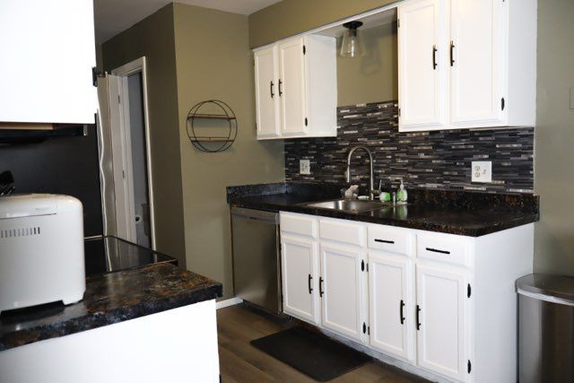 kitchen featuring a sink, decorative backsplash, white cabinets, dishwasher, and dark countertops