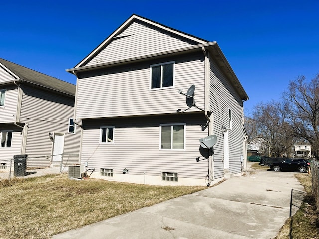 rear view of property featuring concrete driveway and a yard