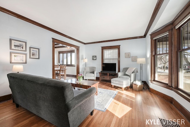 living area featuring baseboards, hardwood / wood-style floors, and ornamental molding