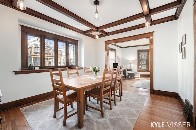 dining area with a wealth of natural light, light wood-style floors, baseboards, and coffered ceiling