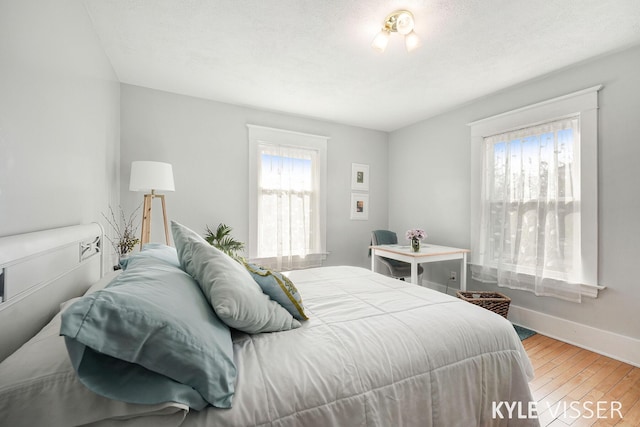 bedroom featuring baseboards, a textured ceiling, and hardwood / wood-style floors