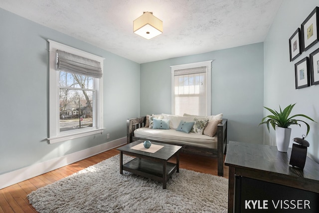 living area featuring wood finished floors, baseboards, a wealth of natural light, and a textured ceiling