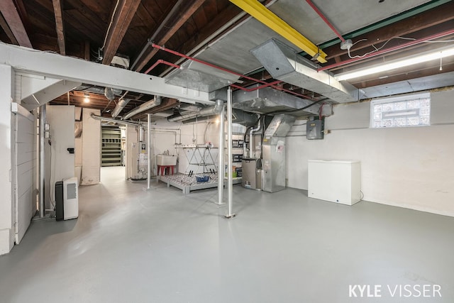 basement featuring heating unit, gas water heater, electric panel, a sink, and fridge