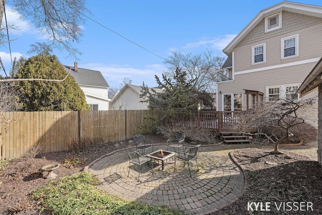 view of yard with a patio, a wooden deck, fence, and a fire pit