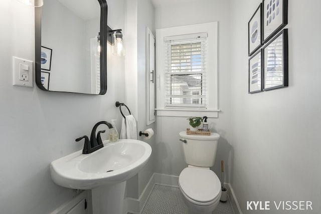 half bathroom featuring a sink, baseboards, and toilet