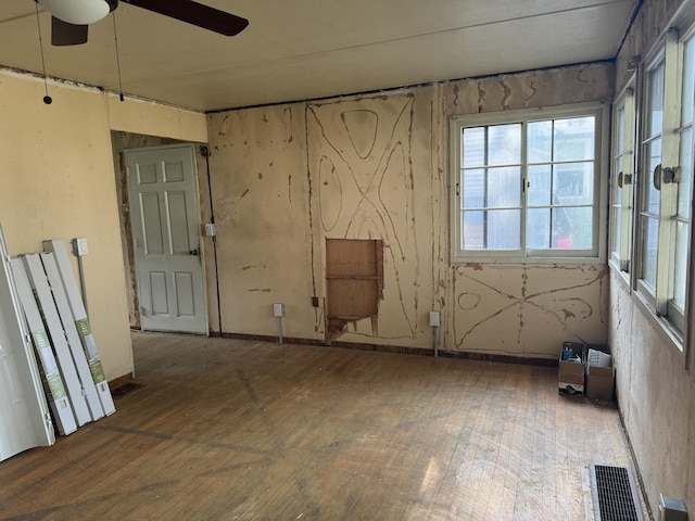 empty room featuring visible vents, a ceiling fan, and hardwood / wood-style flooring