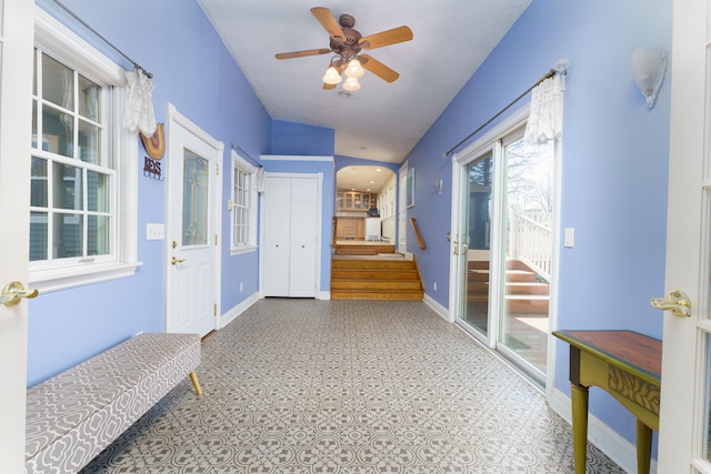 interior space with stairway, baseboards, and arched walkways