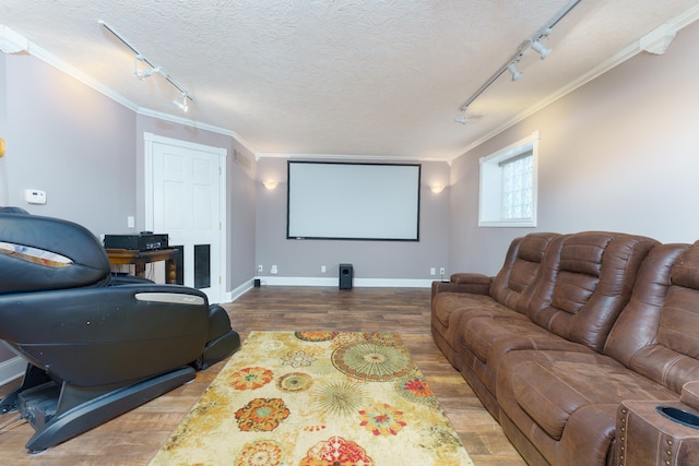 cinema room with baseboards, a textured ceiling, wood finished floors, and crown molding