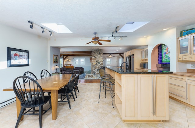 kitchen featuring open shelves, a skylight, freestanding refrigerator, light brown cabinetry, and a textured ceiling