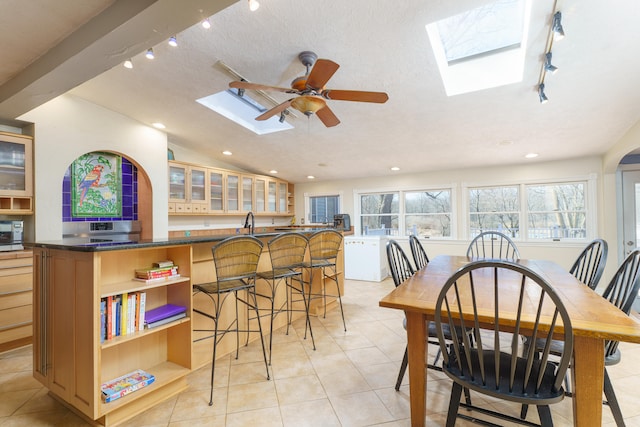 dining area featuring vaulted ceiling with skylight, light tile patterned floors, a wealth of natural light, and a textured ceiling