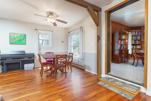 dining space featuring ceiling fan, a baseboard heating unit, and wood finished floors