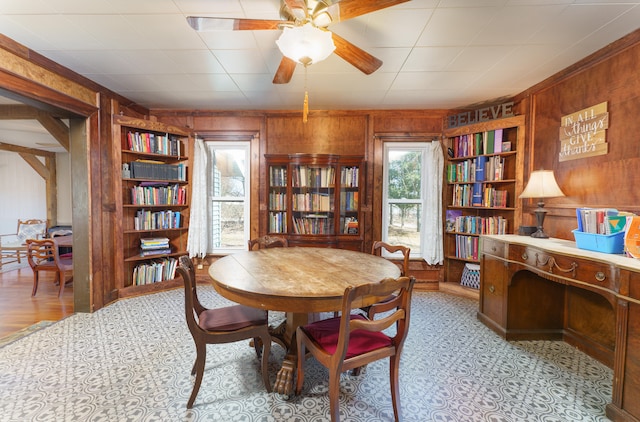 interior space featuring built in features, wood walls, and ceiling fan