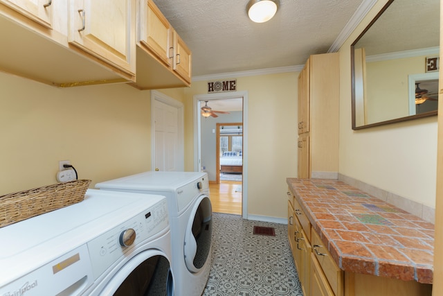 washroom featuring washing machine and dryer, cabinet space, visible vents, and ornamental molding