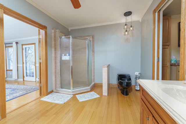 bathroom featuring vanity, baseboards, a shower stall, hardwood / wood-style flooring, and crown molding