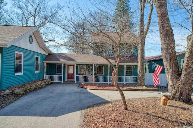 view of front facade featuring roof with shingles, covered porch, and driveway