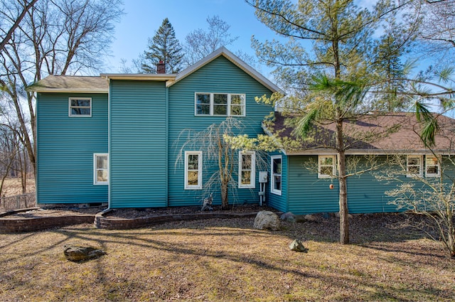 rear view of property featuring a yard and a chimney