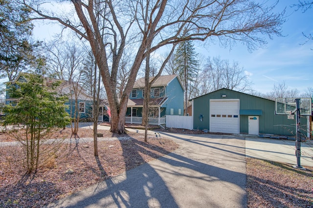 view of front of home with an outdoor structure, fence, a garage, and driveway