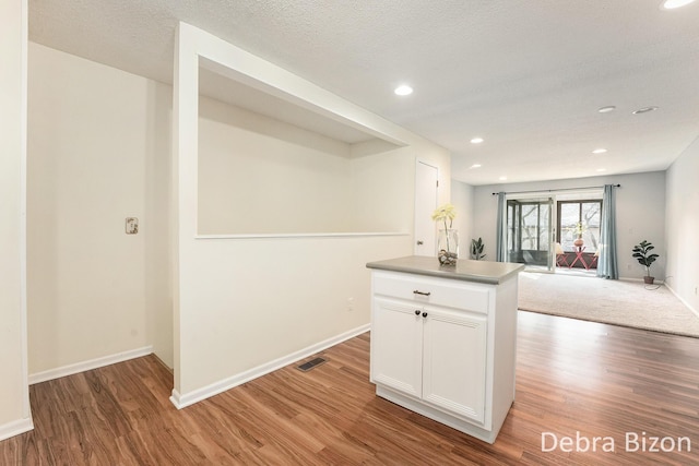 kitchen with light wood finished floors, open floor plan, white cabinetry, and baseboards