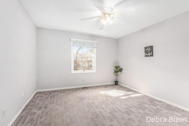 carpeted spare room featuring baseboards, a textured ceiling, and a ceiling fan