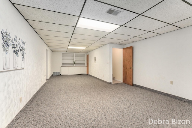 finished basement featuring visible vents, carpet flooring, a paneled ceiling, and baseboards